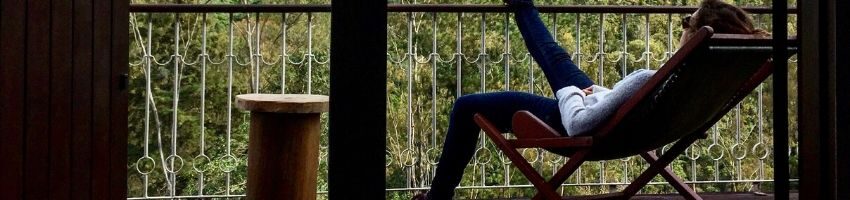 A person reclining on balcony furniture.