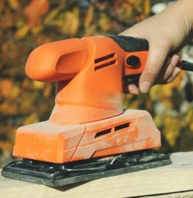 Sanding drywall with electric sander.