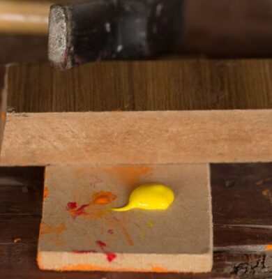 A woodworker using acrylic paint on wood.