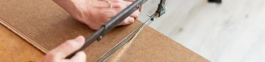 A woodworker sawing a type of manufactured wood.