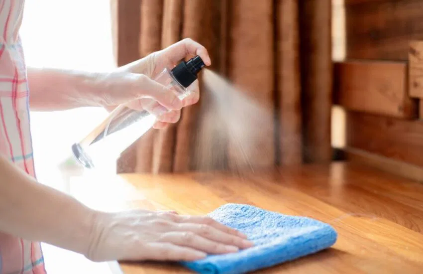 The woman cleans the sticky wooden table.