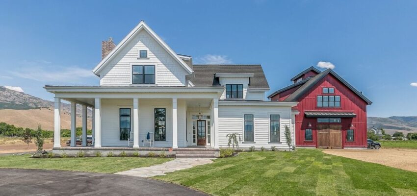 A modern farmhouse with an adjacent red barn.