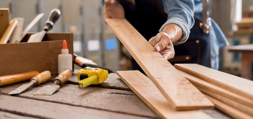 A man working on slats for a window pergola project.