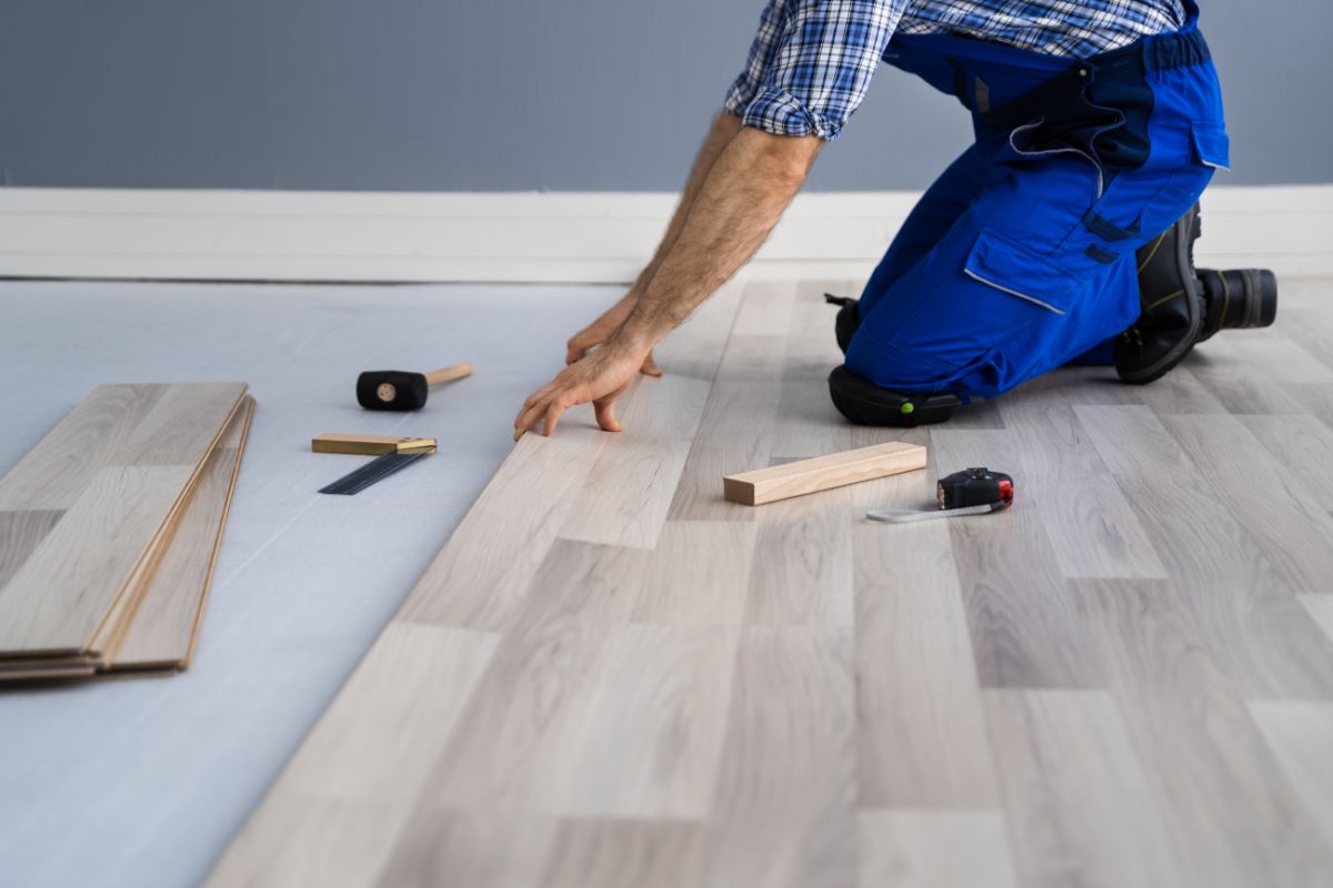 An experienced man installs and patches hardwood floors.