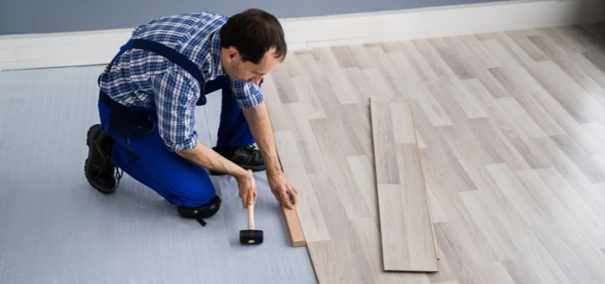 An experienced man patches hardwood floors.