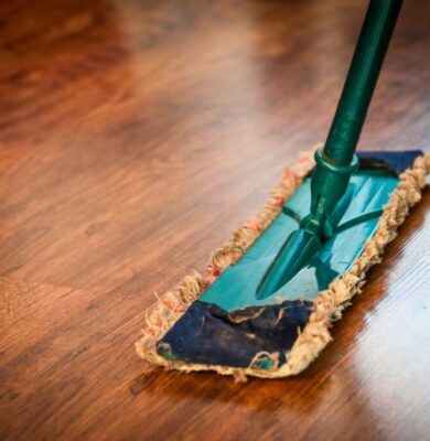 A person mops the floor using a homemade wood floor cleaner that makes the floor shine.