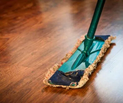 A person mops the floor using a homemade wood floor cleaner that makes the floor shine.