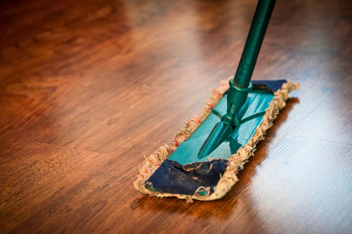 A person mops the floor using a homemade wood floor cleaner that makes the floor shine.