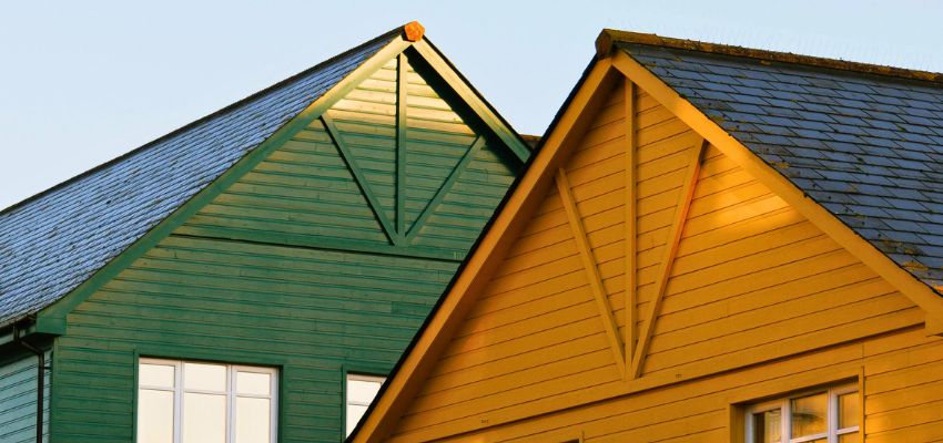 minimum-roof-pitch1 Green and yellow house roofs with steep angles showing examples of minimum roof pitch in residential design.