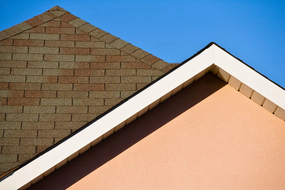 Close-up of a house roof with asphalt shingles under clear sky demonstrating the minimum roof pitch for effective water runoff.
