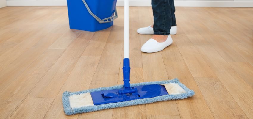 The person uses bleach to clean wooden floors.