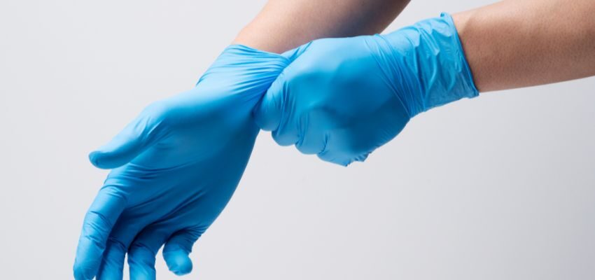 The person wears gloves before using bleach to clean wooden floors.