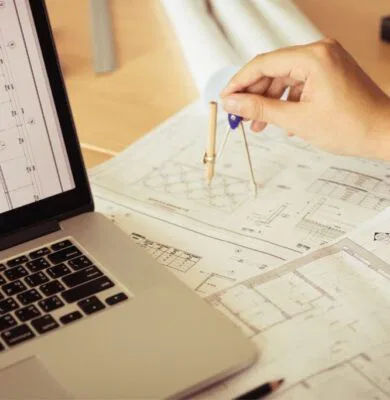 A free landscape design software on a laptop with an architect's hand measuring on paper