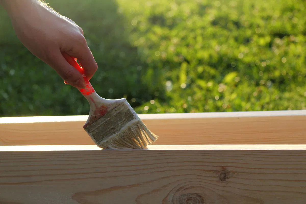 The person treats the wood to preserve and last longer.