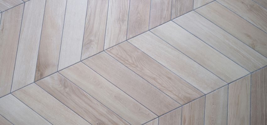 The chevron pattern is crafted by cutting the ends of planks at an angle, allowing them to meet in a pointed, continuous V shape.