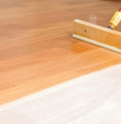 The man is putting a floor finish on his wooden floor.