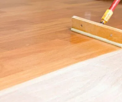 The man is putting a floor finish on his wooden floor.