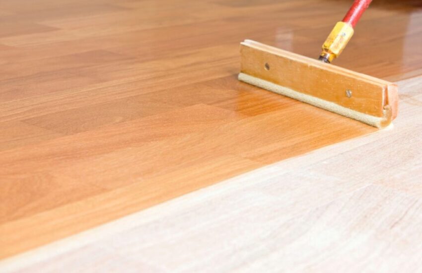 The man is putting a floor finish on his wooden floor.