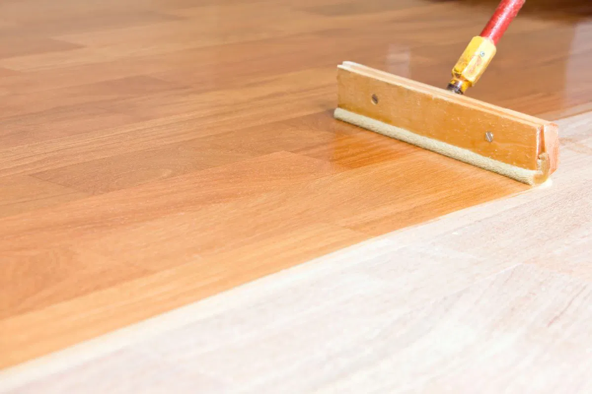 The man is putting a floor finish on his wooden floor.