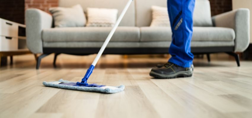 The man used a mop to remove the splashed water from the wooden floor.