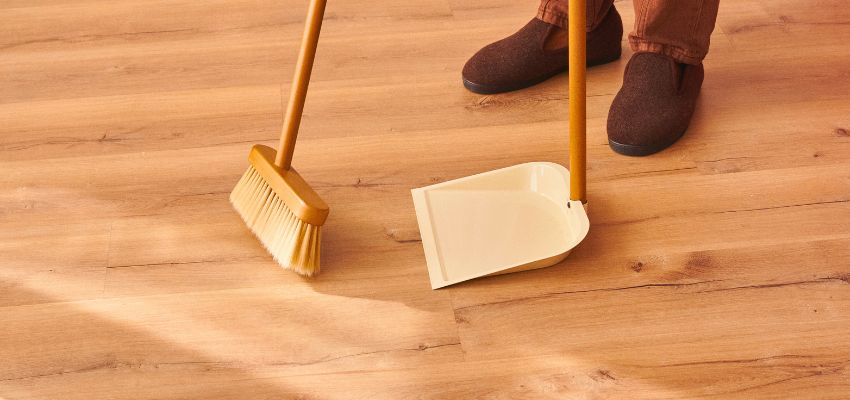 how-to-clean-unsealed-wood-floors2 A man sweeping the floor as part of the key steps on how to clean unsealed wood floors.