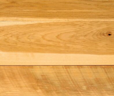 Detailed macro view of smooth, light-toned hickory wood surface showing rich grain patterns, natural knots, and warm golden hues characteristic of premium hickory wood.