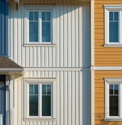 Close-up of blue and white houses with vertical wood siding next to a yellow house with horizontal siding