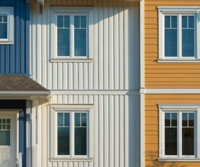 Close-up of blue and white houses with vertical wood siding next to a yellow house with horizontal siding