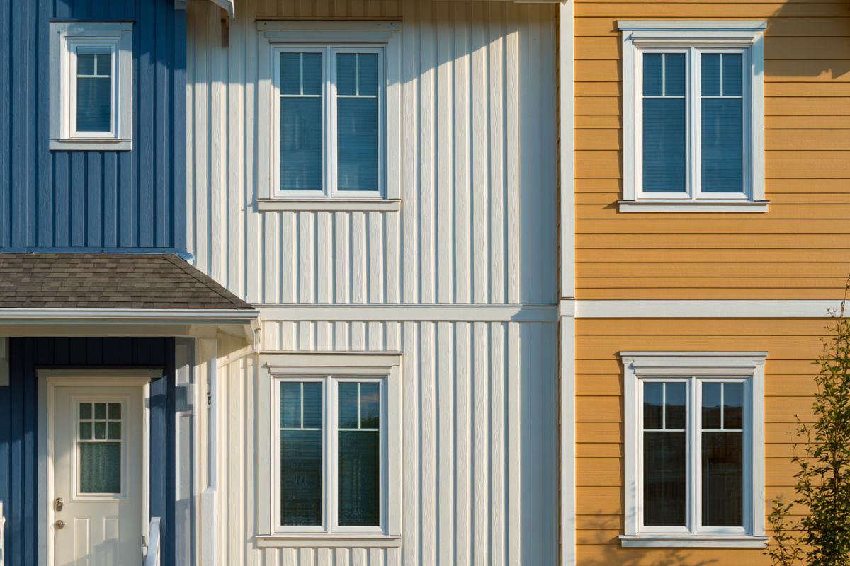 Close-up of blue and white houses with vertical wood siding next to a yellow house with horizontal siding