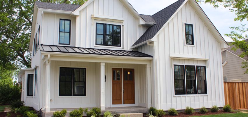 Two-story white house with vertical wood siding and black metal roof accents