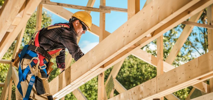 SPF wood framing during house construction with a worker in a yellow hard hat installing beams