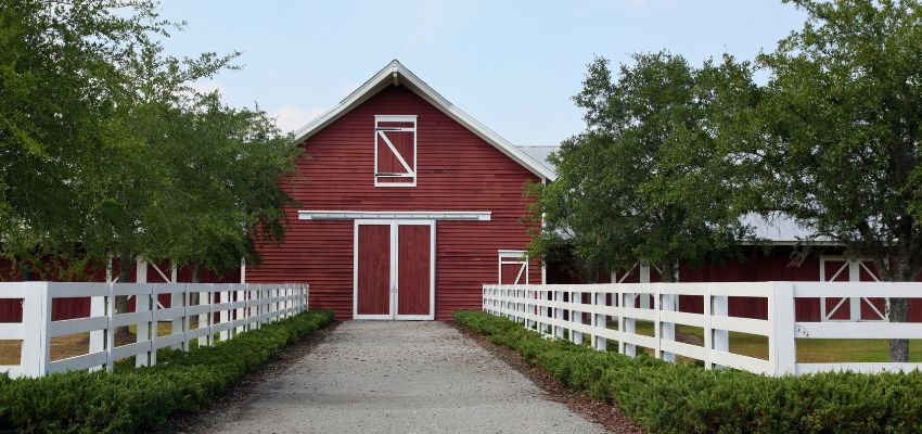 Classic red barn-style structure with white fencing, an example of traditional barndominium houses.