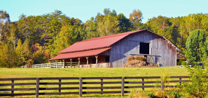 Traditional wooden barn with a red roof, one of the common types of barns found on farms.
